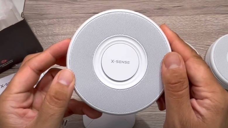 Hands holding X-Sense smoke alarm