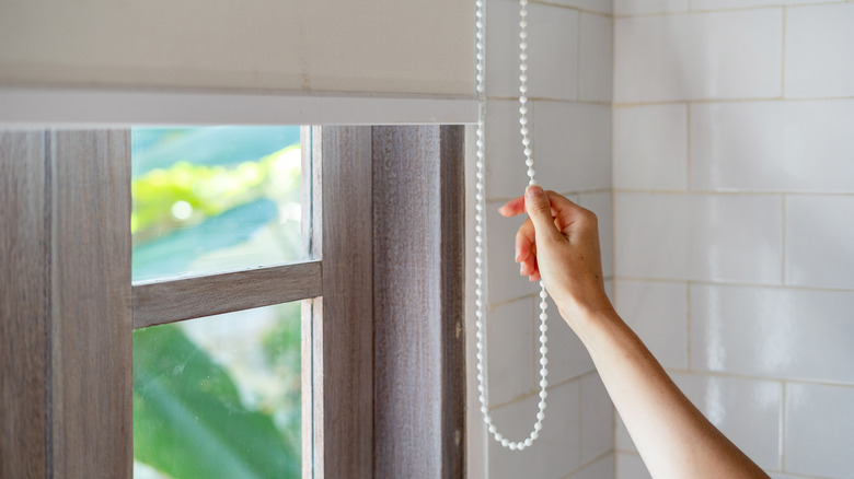 woman's hand closing bathroom blinds