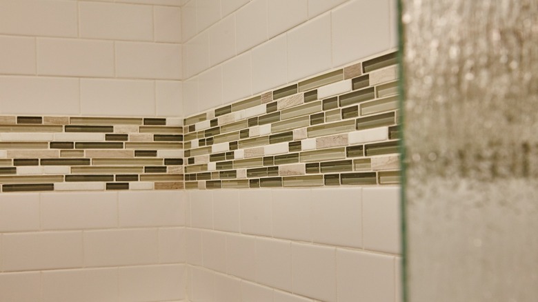 A tile accent strip is installed in a shower