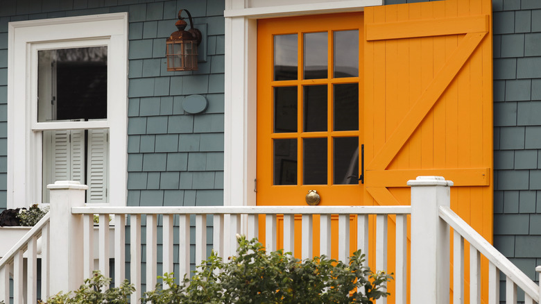 Dark blue-green house with a bright orange front door