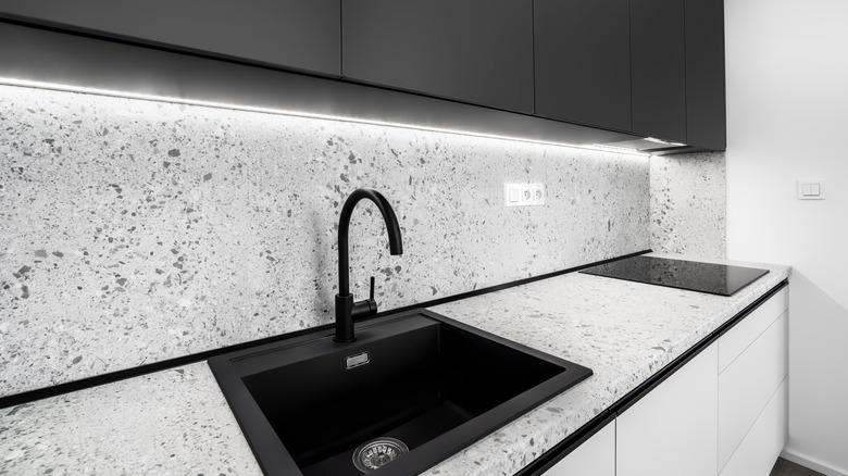 A modern black and white kitchen with terrazzo countertop and backsplash