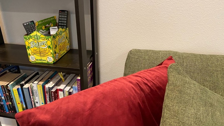 Beer box with remotes on bookshelf