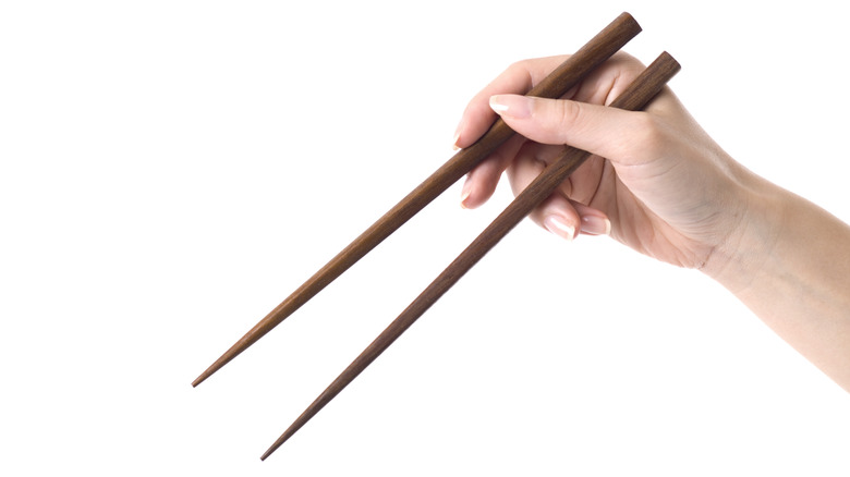 hands holding a pair of chopsticks