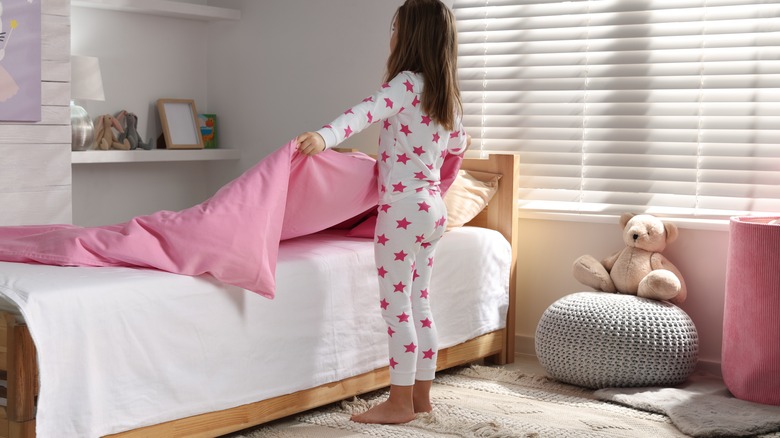 little kid making bed