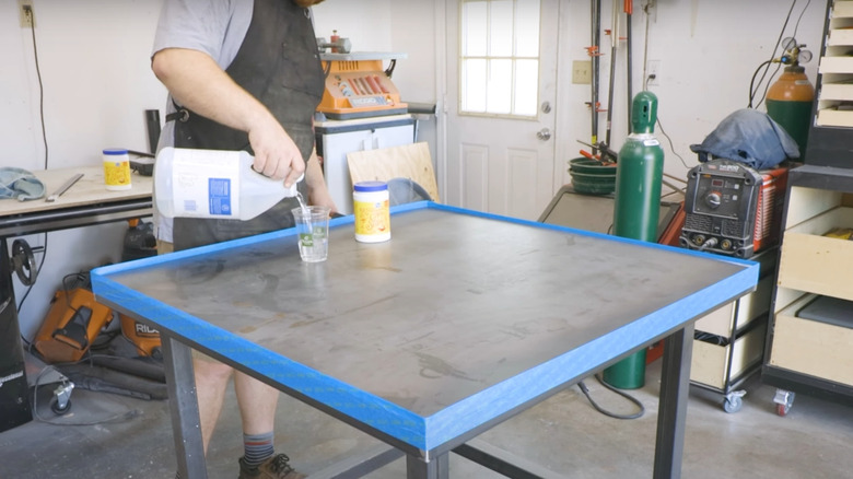 man pouring DIY vinegar cleaner on steel garage table