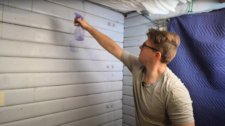 man spraying mold on interior garage wall with vinegar