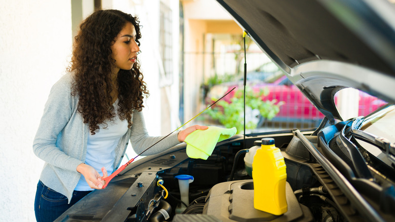 woman checking oil in home garage