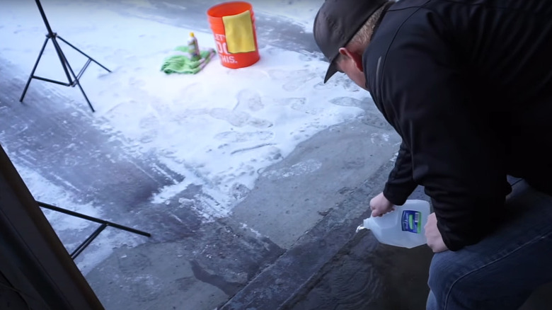 man pouring boiling water on garage floor entryway