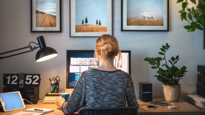 A table lamp lighting a home office desk where a person is typing