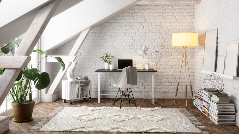 An attic home office illuminated by a floor lamp with a yellow shade