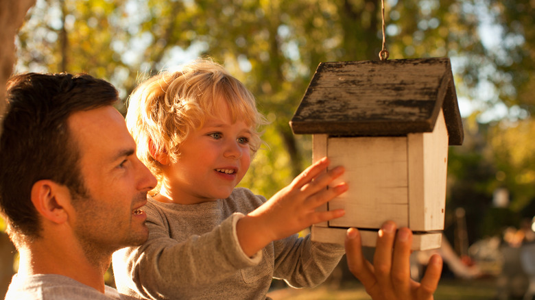 Father and son hanging cream birdhouse