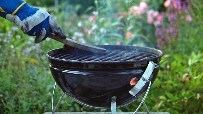 person cleaning dirty grill grate