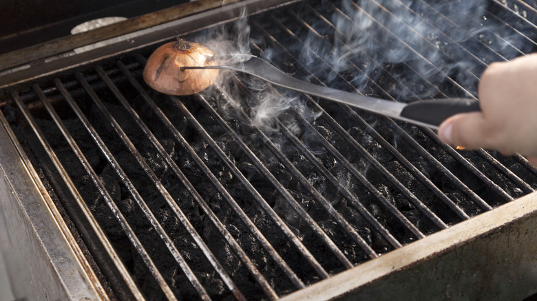 Rubbing a half of an onion on a grill grate