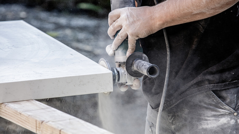 Worker finishing off edges of countertop with sander