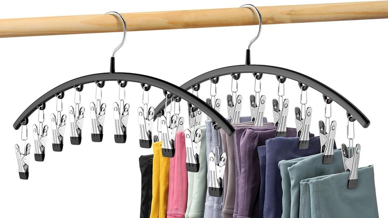 Two arched hangers with clips hang on a closet rod