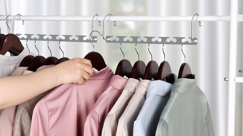 A person hangs a pink shirt on a space saving hanger