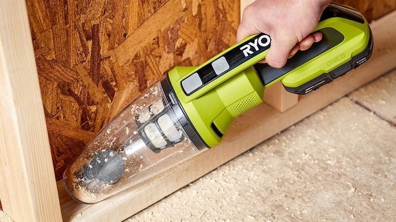 Person using a hand vacuum on framing