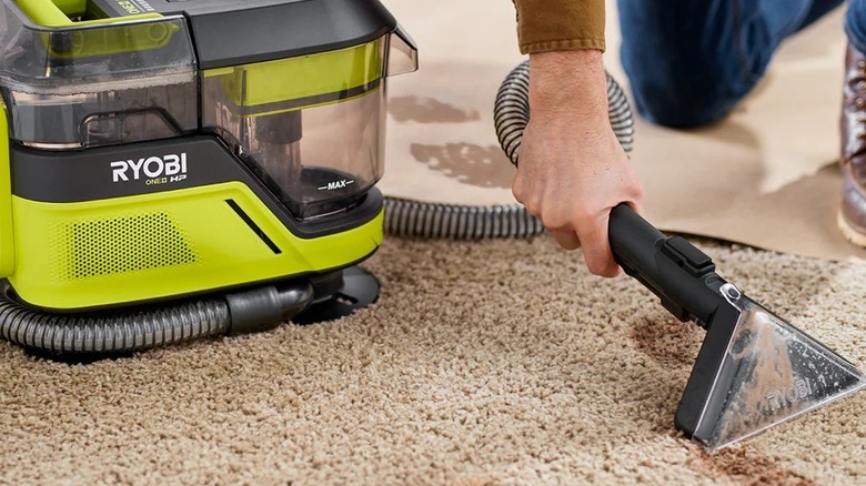 Person cleaning stains on carpet with a Ryobi spot cleaner