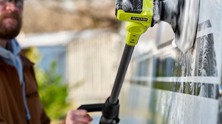 Man washing siding with a Ryobi power scrubber