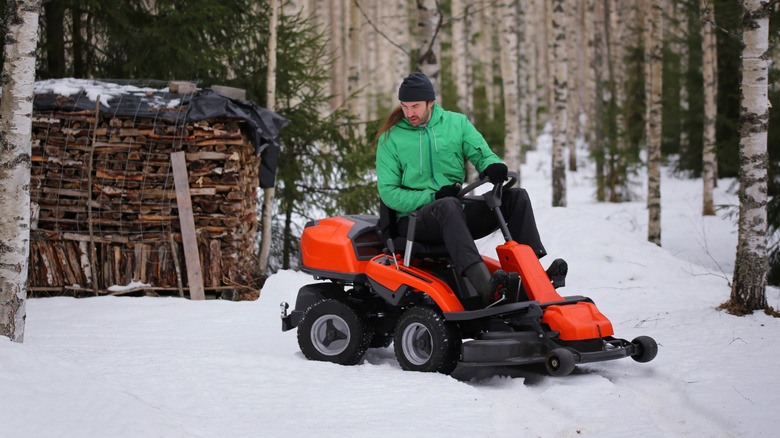 Man on a riding lawn mower in the snow