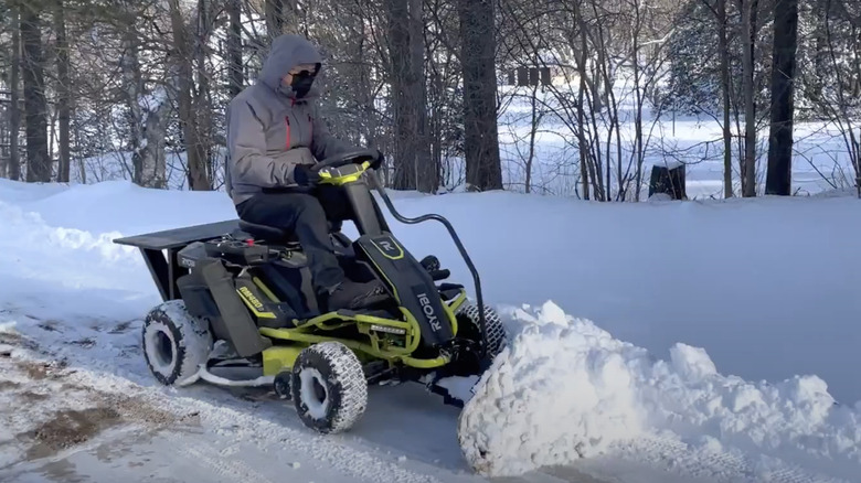 Man on Ryobi Riding Mower with snow plow attachment