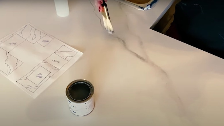 A person painting a countertop with a marble effect