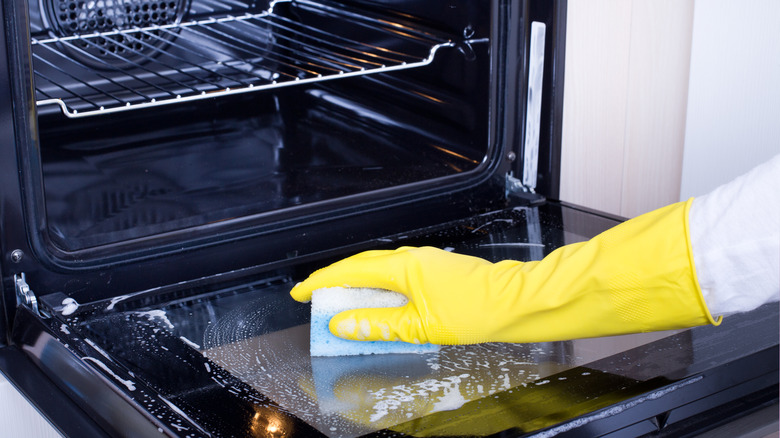 Gloved hand cleaning oven