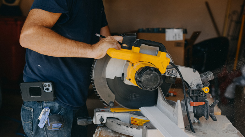 A person in a blue shirt using a yellow power saw