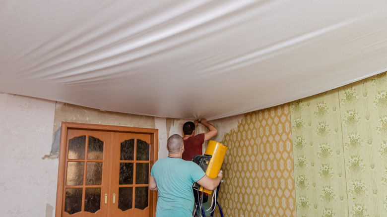 Workers installing stretched fabric over ceiling