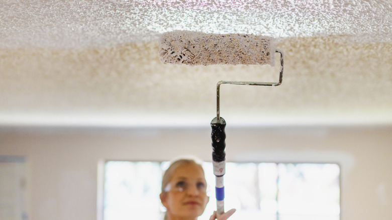 Woman painting popcorn ceiling white