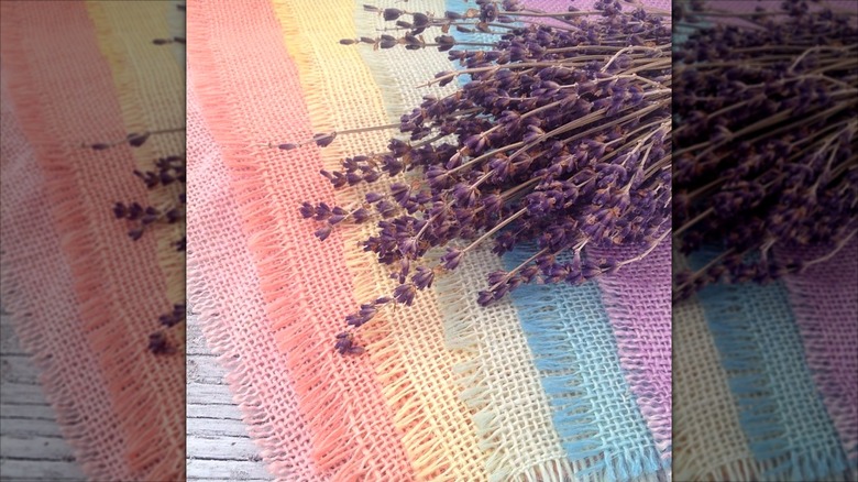 Multicolored pieces of dyed burlap underneath a bundle of dried lavender