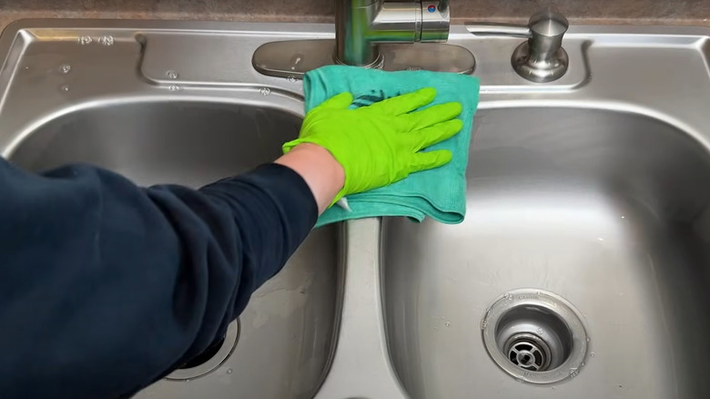 man drying stainless steel sink with teal microfiber cloth