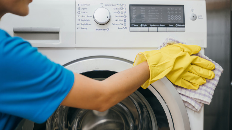 woman wiping white dryer exterior with soft cloth