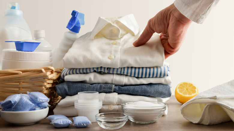 hand reaching for clean stack of laundry amidst natural cleaning products