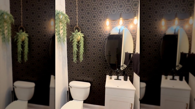 Bathroom with dark patterned wallpaper and hanging plants