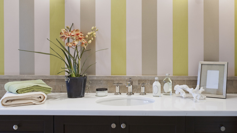 Bathroom with vertical striped wallpaper in pink, green, and tan