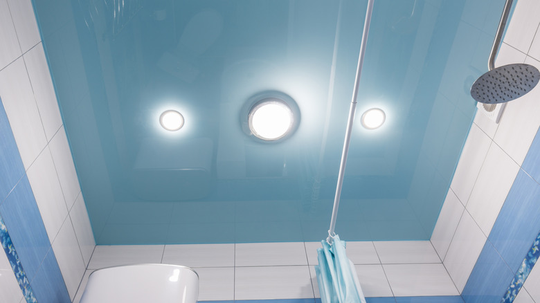 Blue ceiling above shower in bathroom with three lights