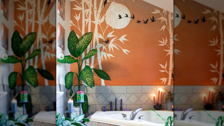 Woman in bathtub looking at orange bamboo mural