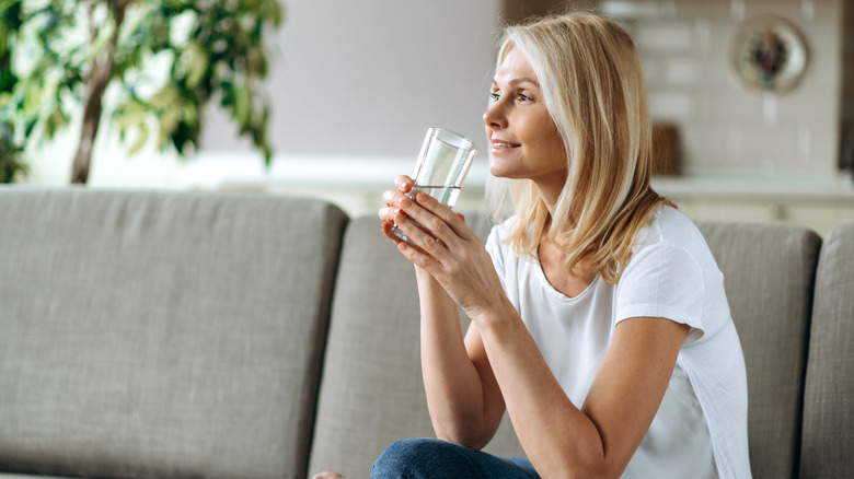 woman drinking water on couch 