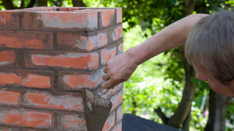person patching up chimney mortar