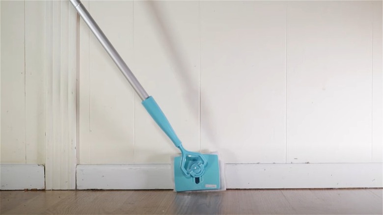 Light blue Baseboard Buddy being used to clean white baseboard