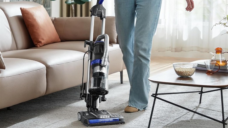 Woman vacuuming gray carpet with Eureka OmniVerse vacuum cleaner