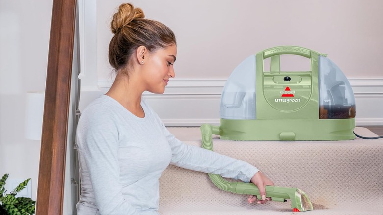 woman using Bissell Little Green Machine on beige carpet stairs