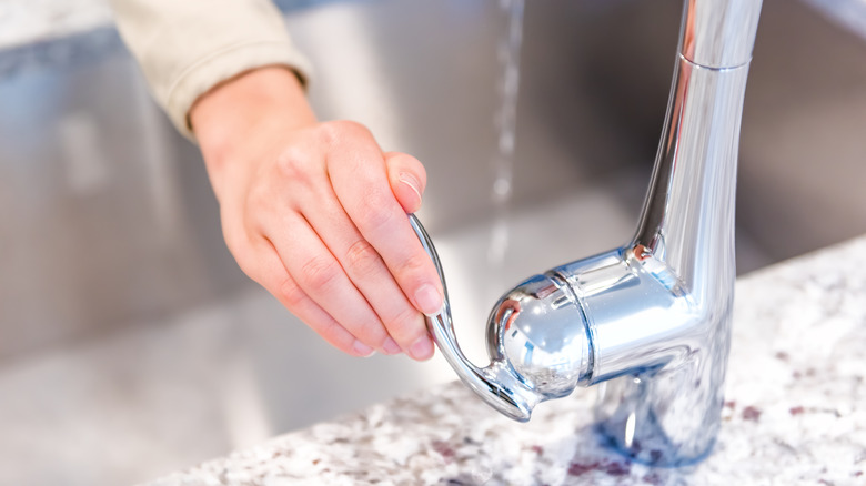 Hand turning on the kitchen faucet