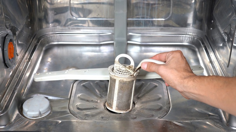 Person's hand cleaning the sprayer arm nozzle