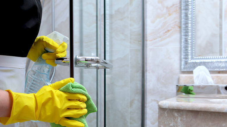 person cleaning shower with gloves