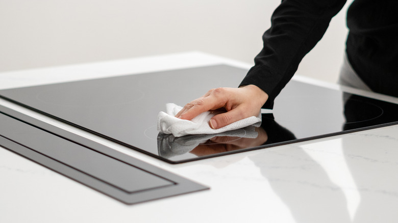 woman wiping glass top stove