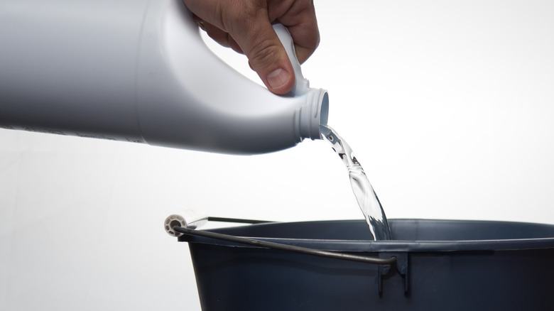 Hand pouring bleach from bottle