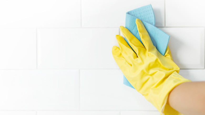 Gloved hand cleaning tiles