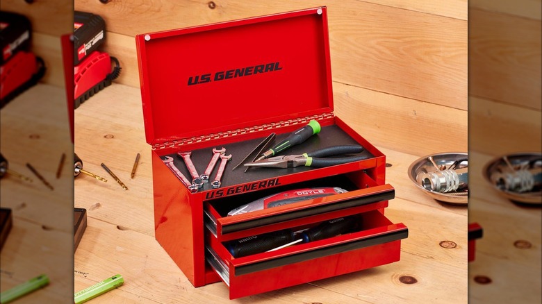 An opened red mini toolbox is filled with pliers, wrenches, and other small tools